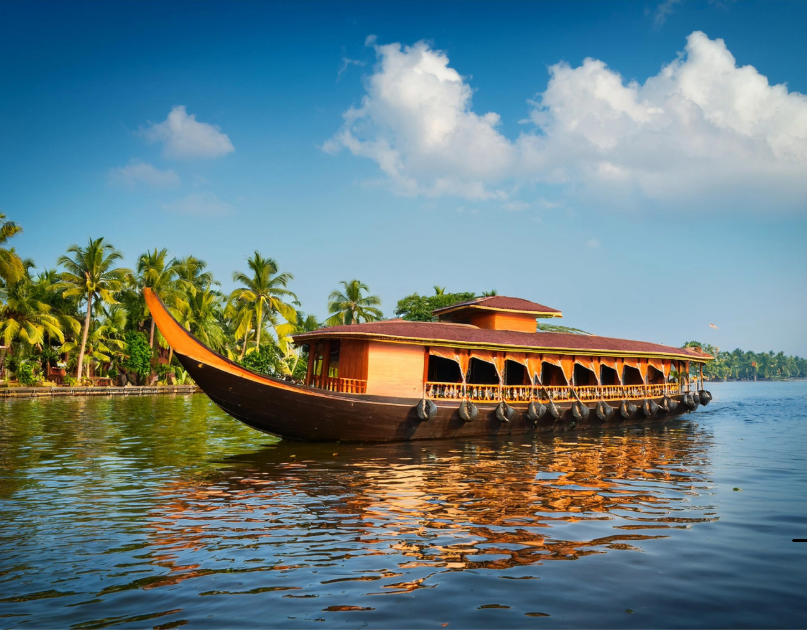 Barco tradicional navegando por los tranquilos backwaters de Kerala entre palmeras y paisajes tropicales.